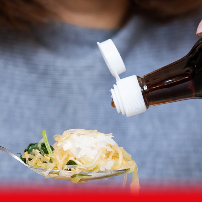 woman pouring sauce on food